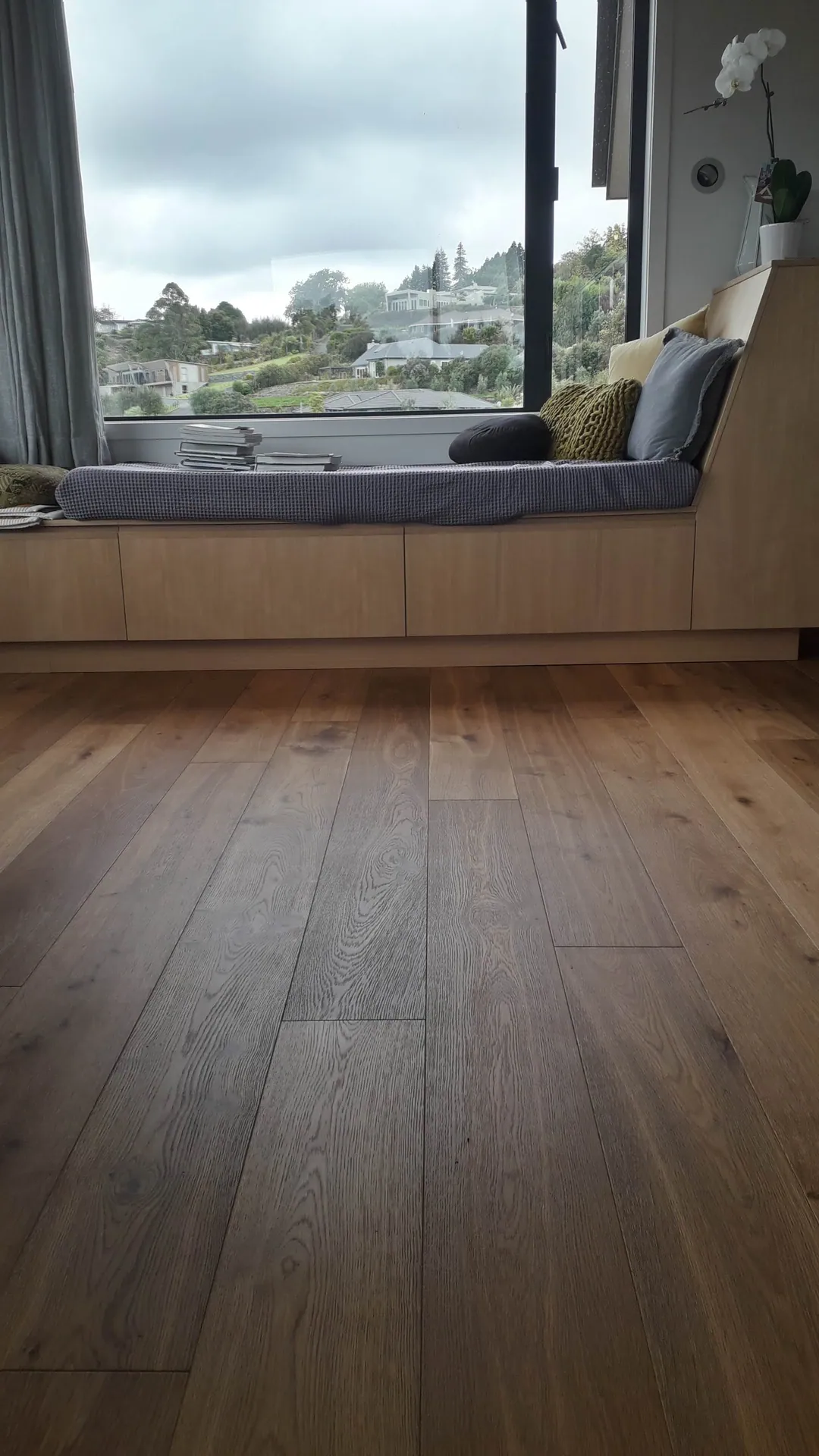 Dark oak floor under a window seat.