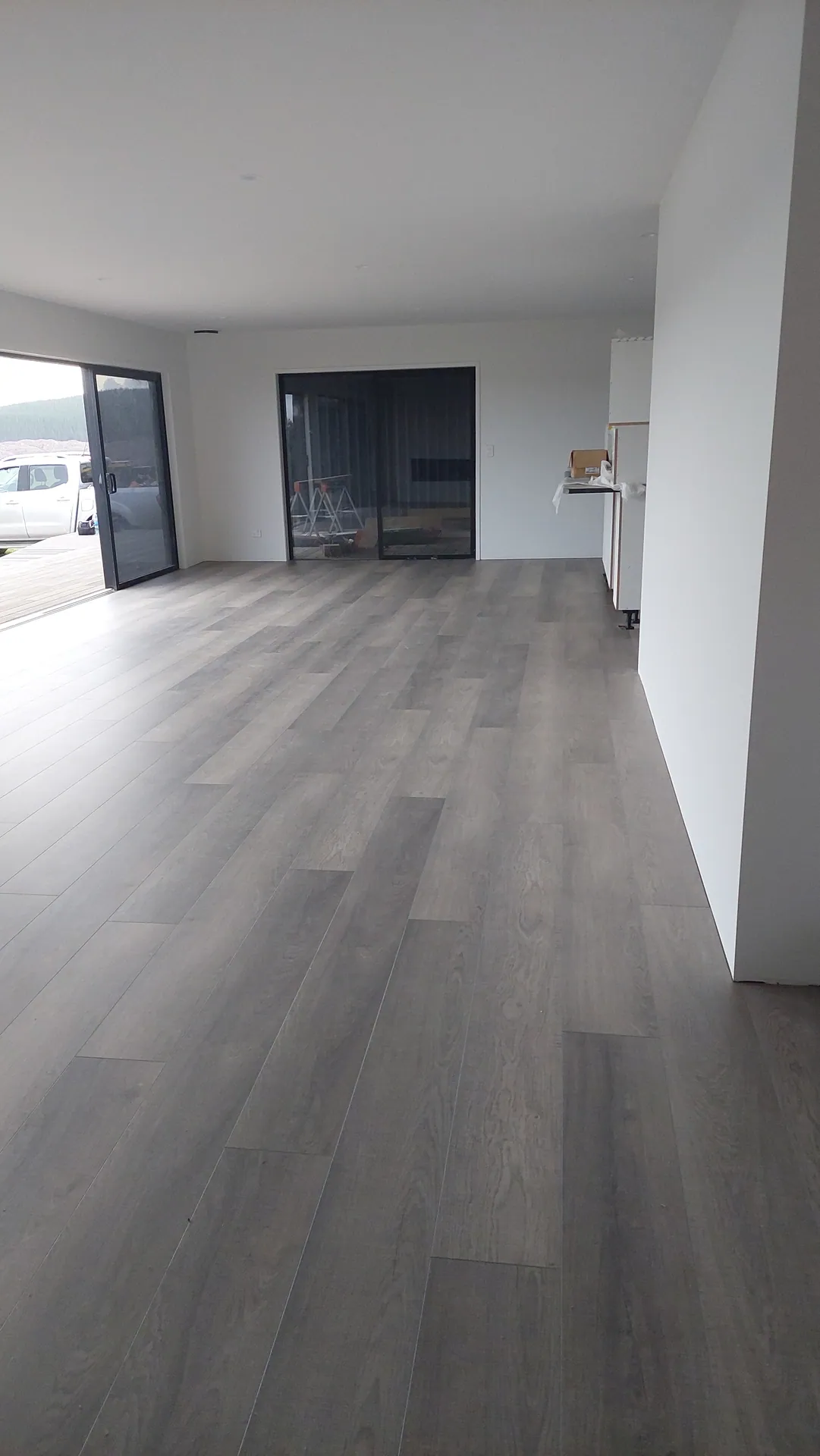 Grey timber-look floor in a long open room.