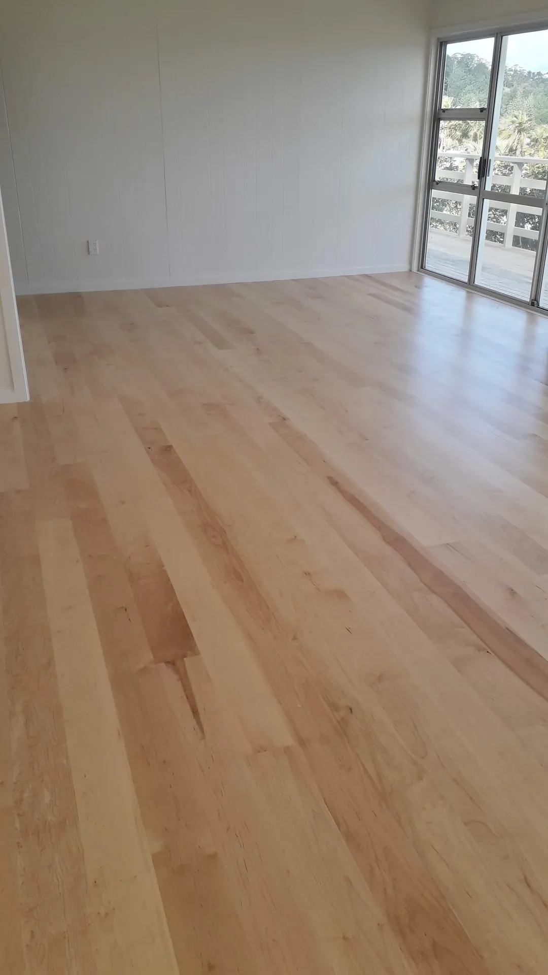 Light timber floor in a room with sea-view windows.