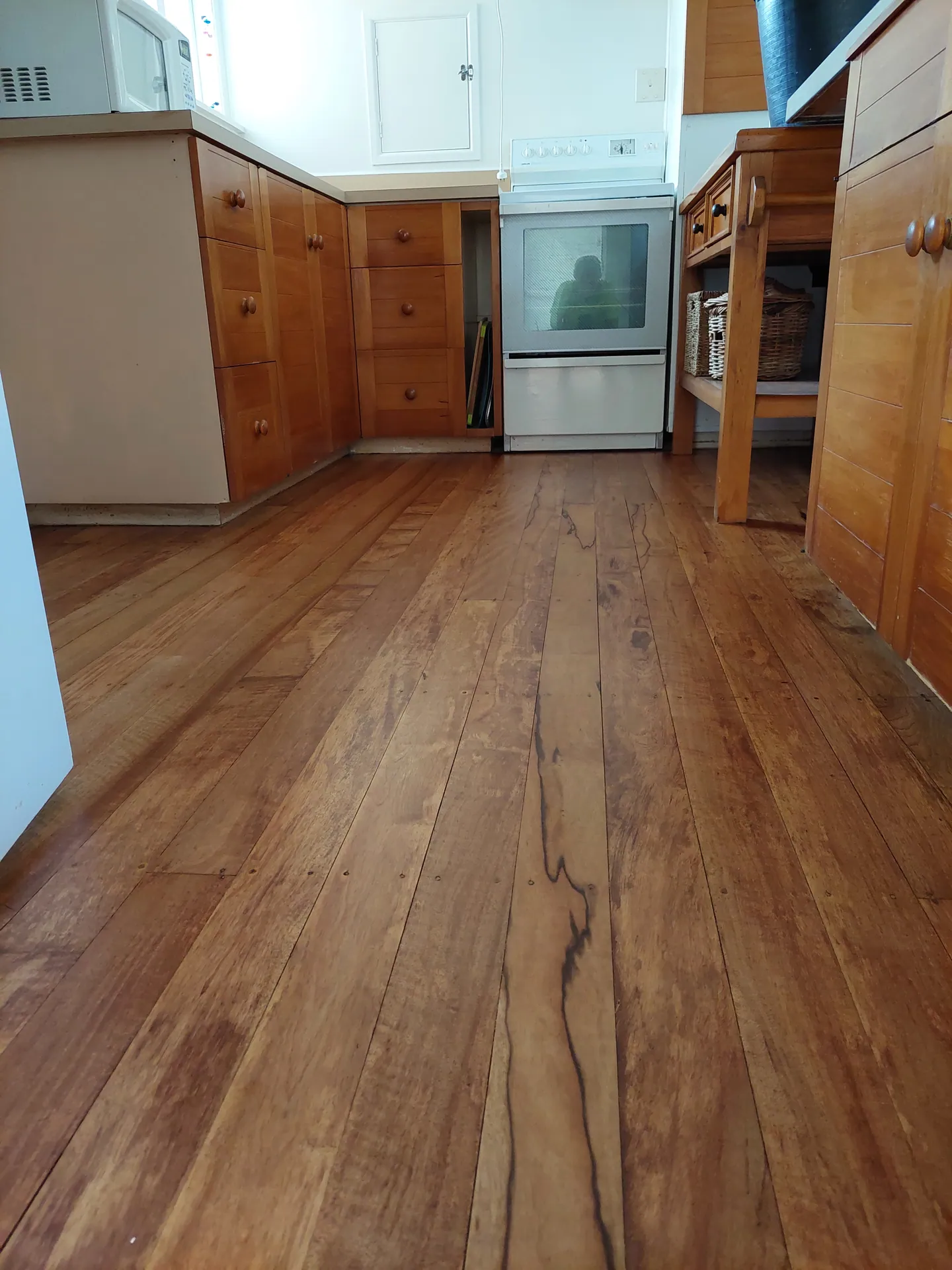 Refinished native timber floorboards with strong figure running through a kitchen with timber cabinets.