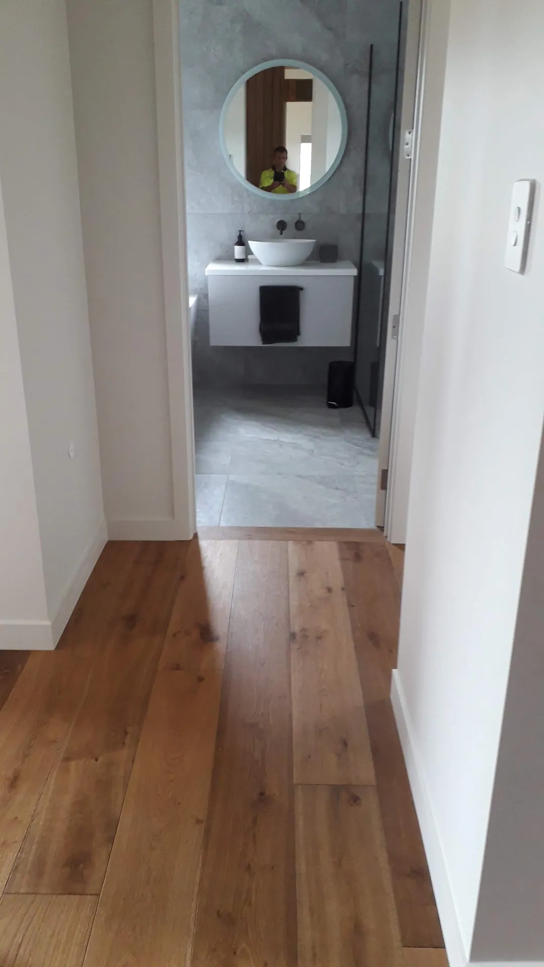 Oak floor down a hallway to a bathroom.
