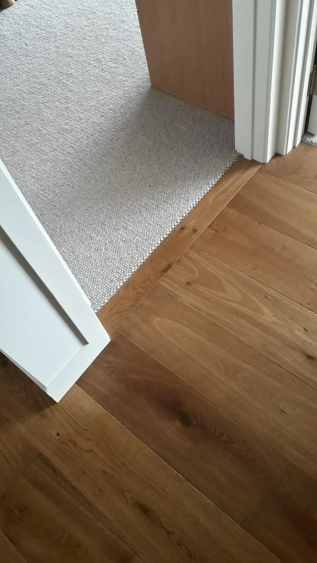 Oak floor meeting carpet at a doorway.