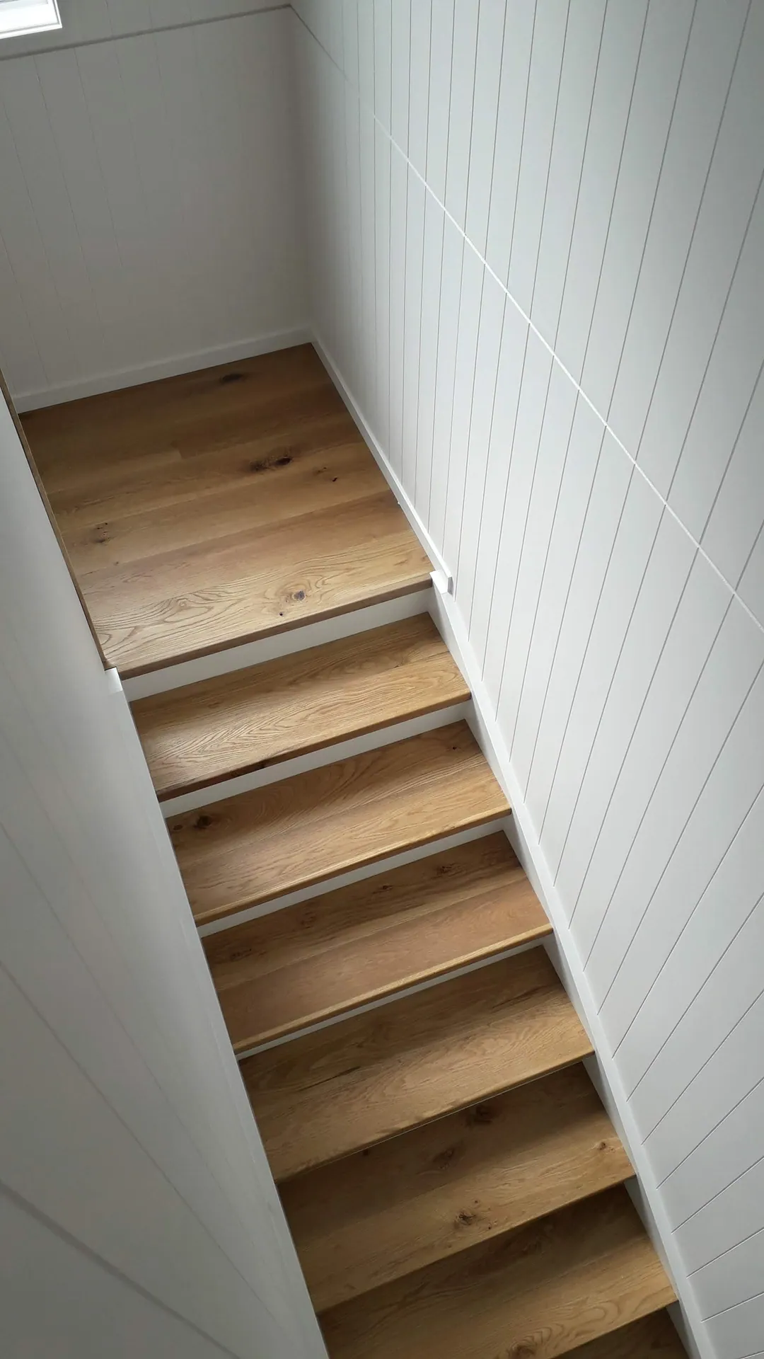 Oak stair treads beside a panelled wall.