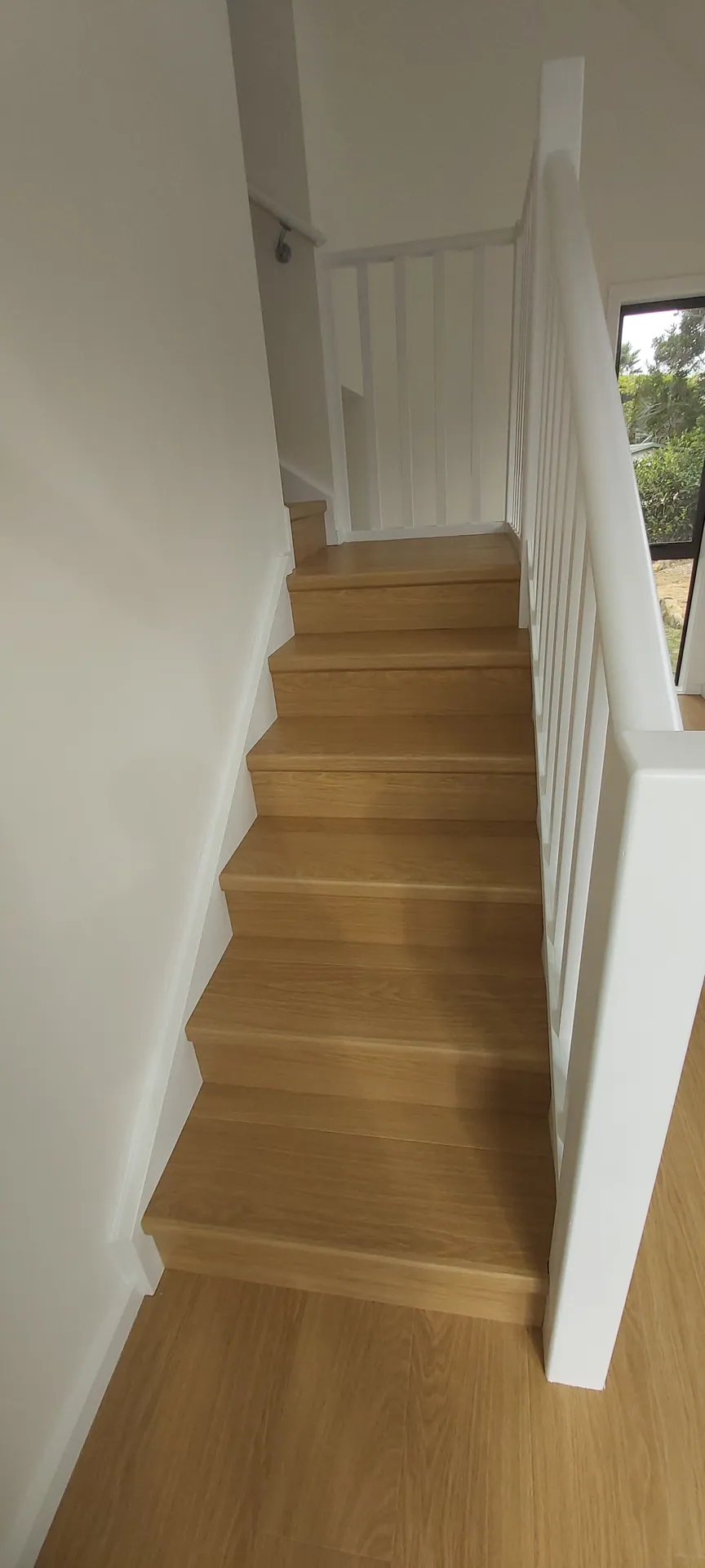 Straight staircase with timber treads and risers and a painted white balustrade.