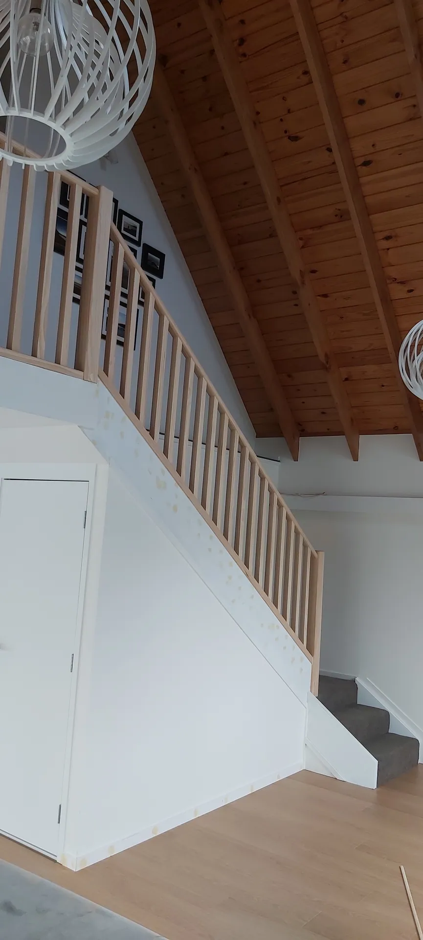 Pine balustrade following a staircase beneath a raking timber-lined ceiling.