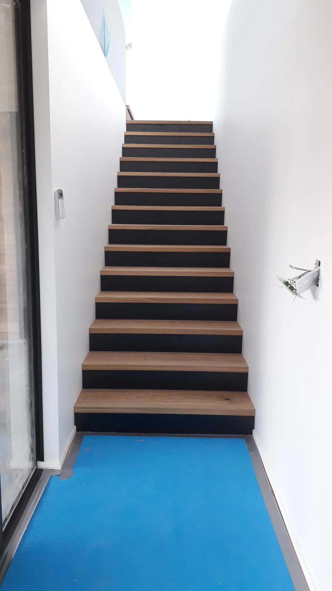 Timber stair treads up a white stairwell.