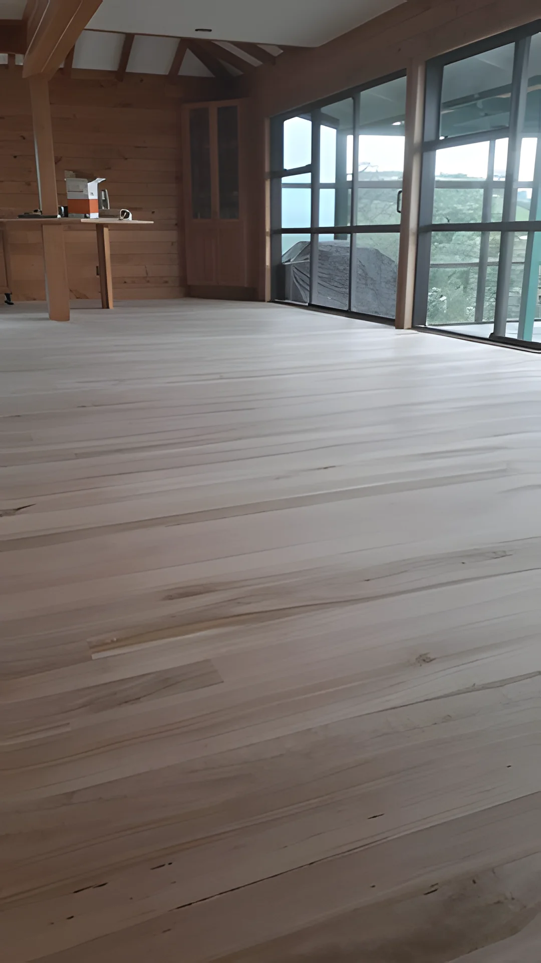 Wide light timber floor by big windows.