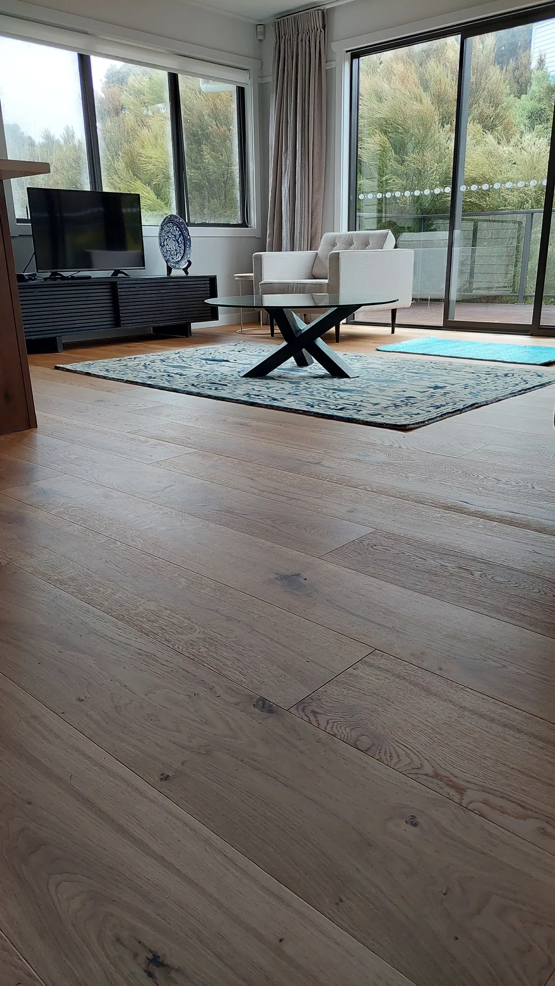Wide oak floor in a lounge with a rug.