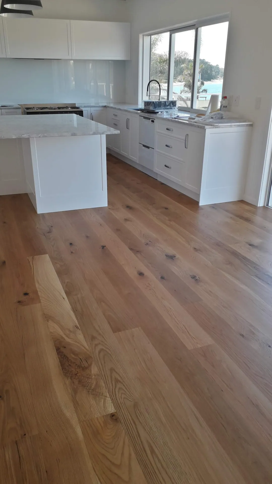 Wide oak floor in a white kitchen.